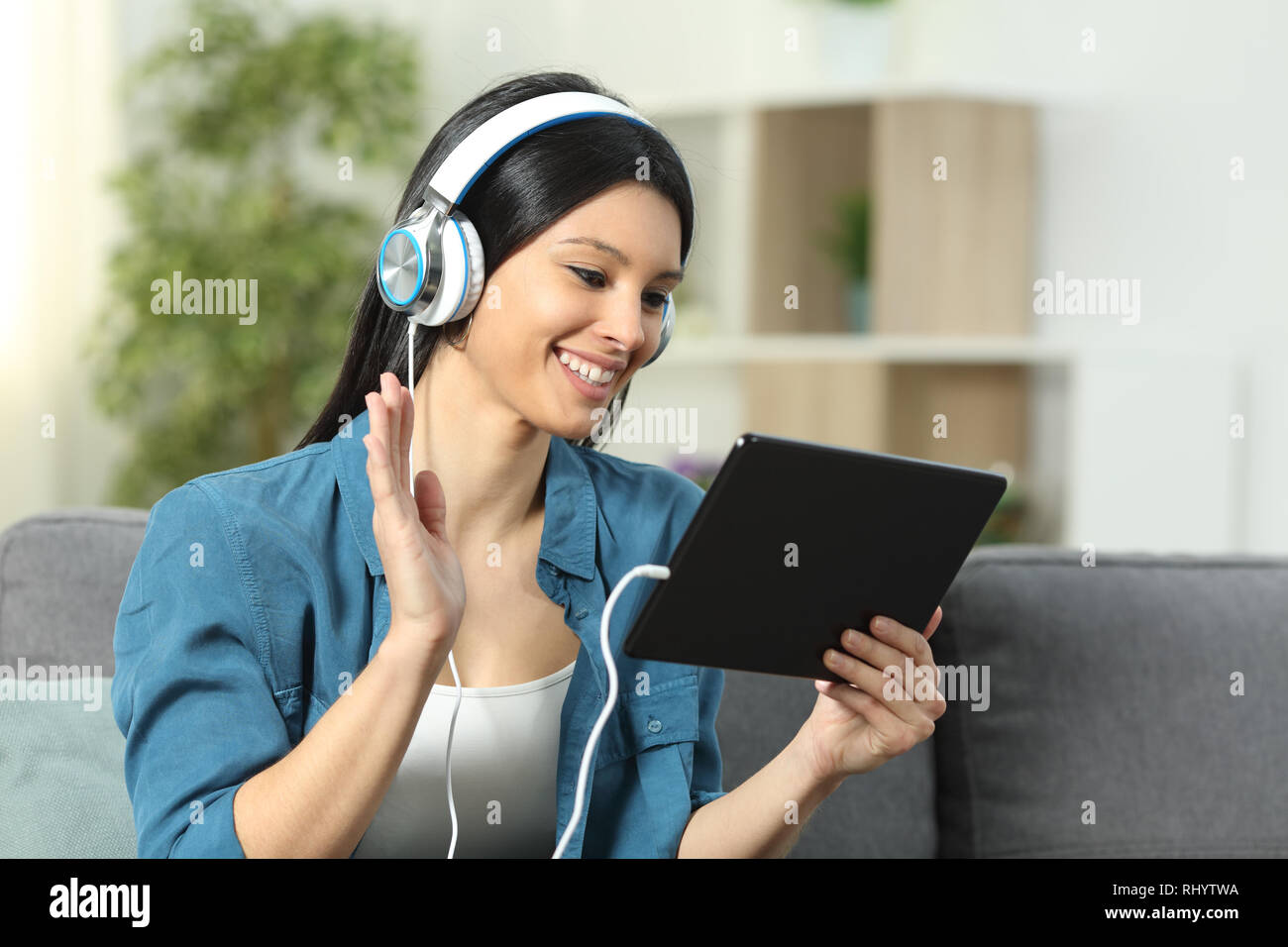 Happy lady Gruß in einer Videokonferenz auf einem Tablett auf einer Couch im Wohnzimmer zu Hause sitzen Stockfoto