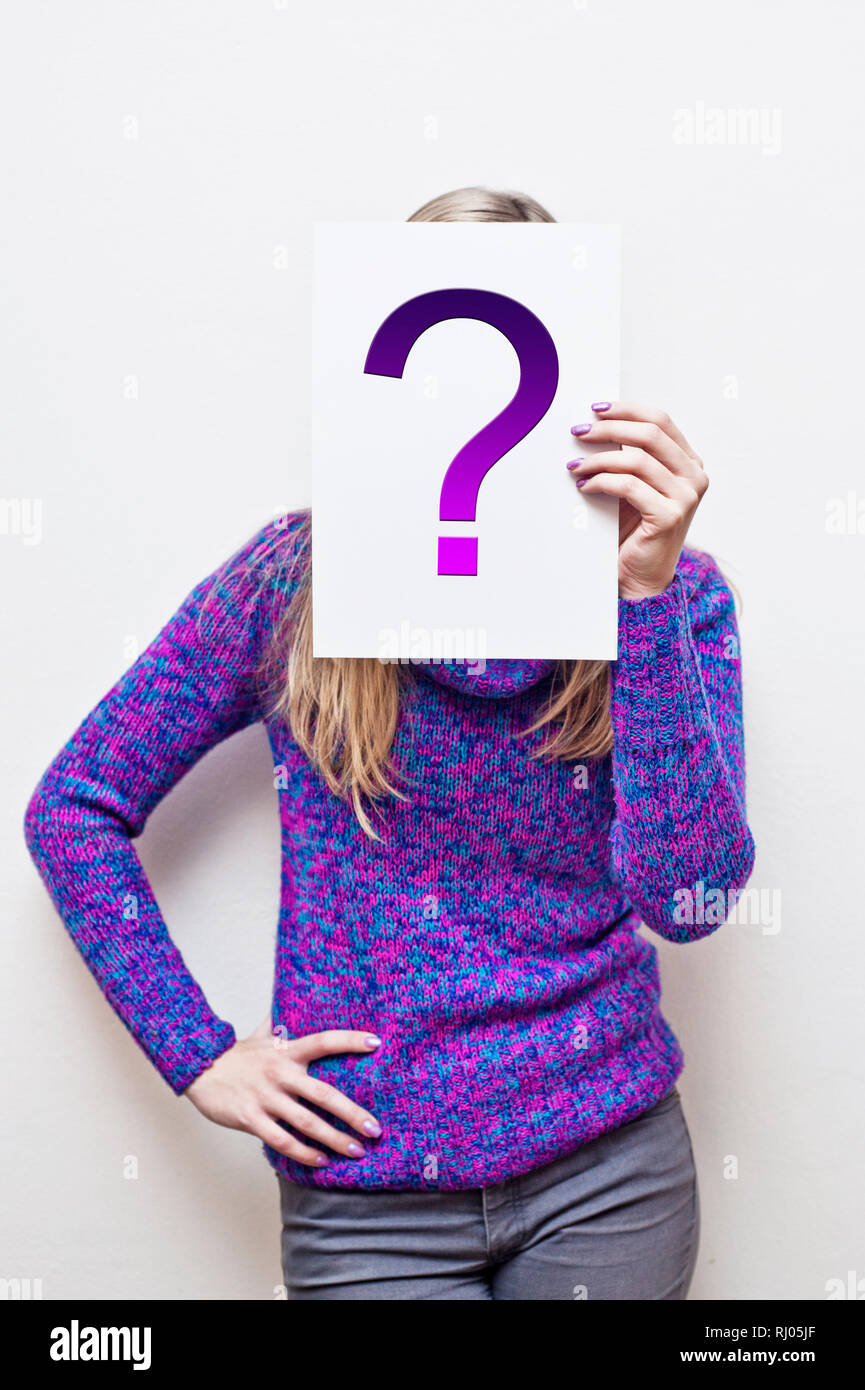 Frau mit einem Papier vor Ihrem Gesicht mit Fragezeichen Stockfoto