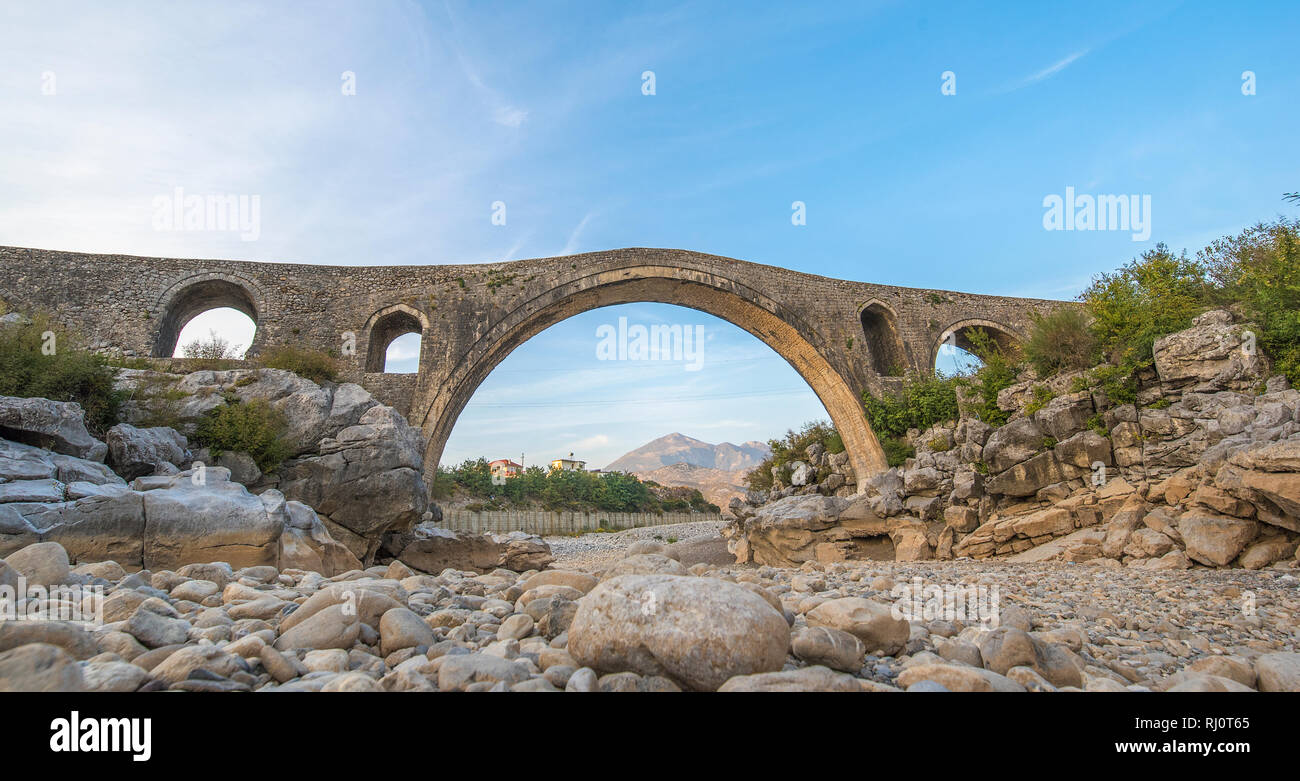 Die mesi Brücke (Ura e Mesit) in Mes, Albanien, in der Nähe von Shkodra. Ein alter Stein osmanische Brücke - die größte im Land. Trockenen Fluss und die Berge Stockfoto