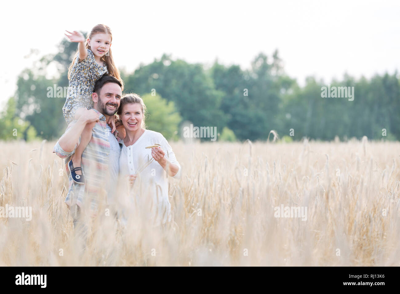 Lächelnd Eltern mit Tochter steht man inmitten Weizen auf der Farm Stockfoto