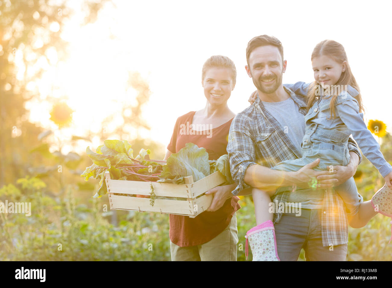 Portrait von lächelnden Familie mit Gemüse in der Kiste auf dem Bauernhof Stockfoto