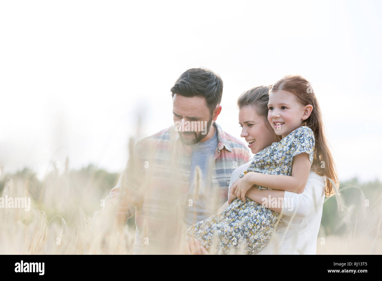 Lächelnd Eltern mit Tochter inmitten von Weizen auf der Farm Stockfoto