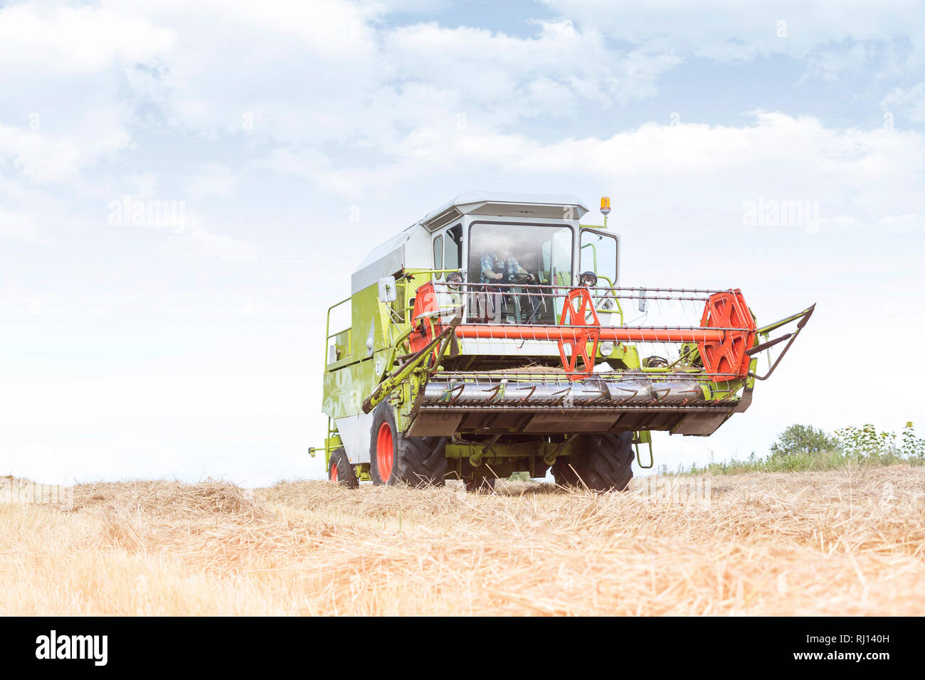 Bauer fahren Feldhäcksler auf Feld an der Farm gegen Sky Stockfoto