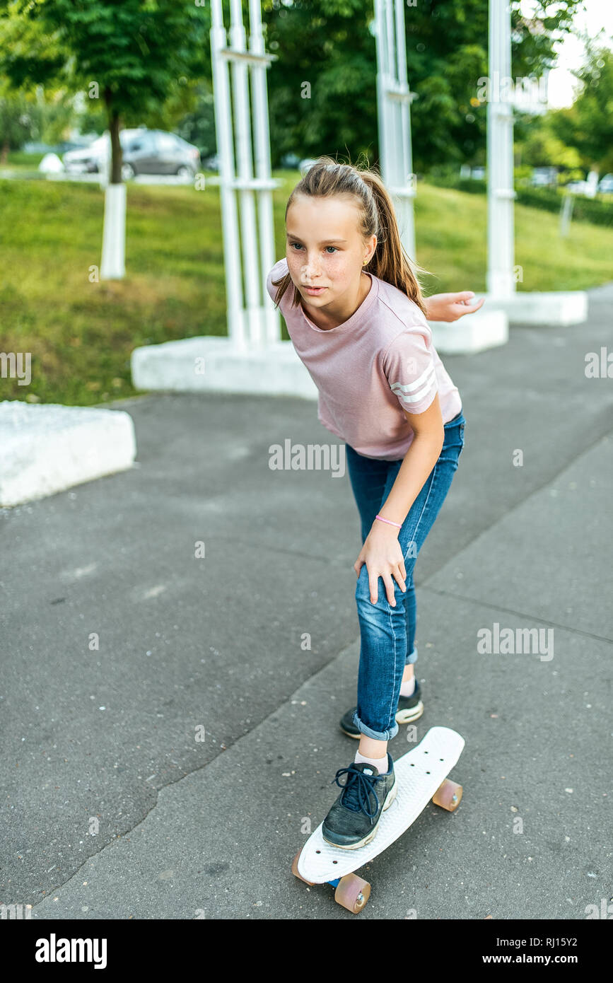 Mädchen Teenager 10-15 Jahre alt, reiten ein Skateboard. Im Sommer in der  Stadt in lässigen Jeans und Turnschuhe Stockfotografie - Alamy