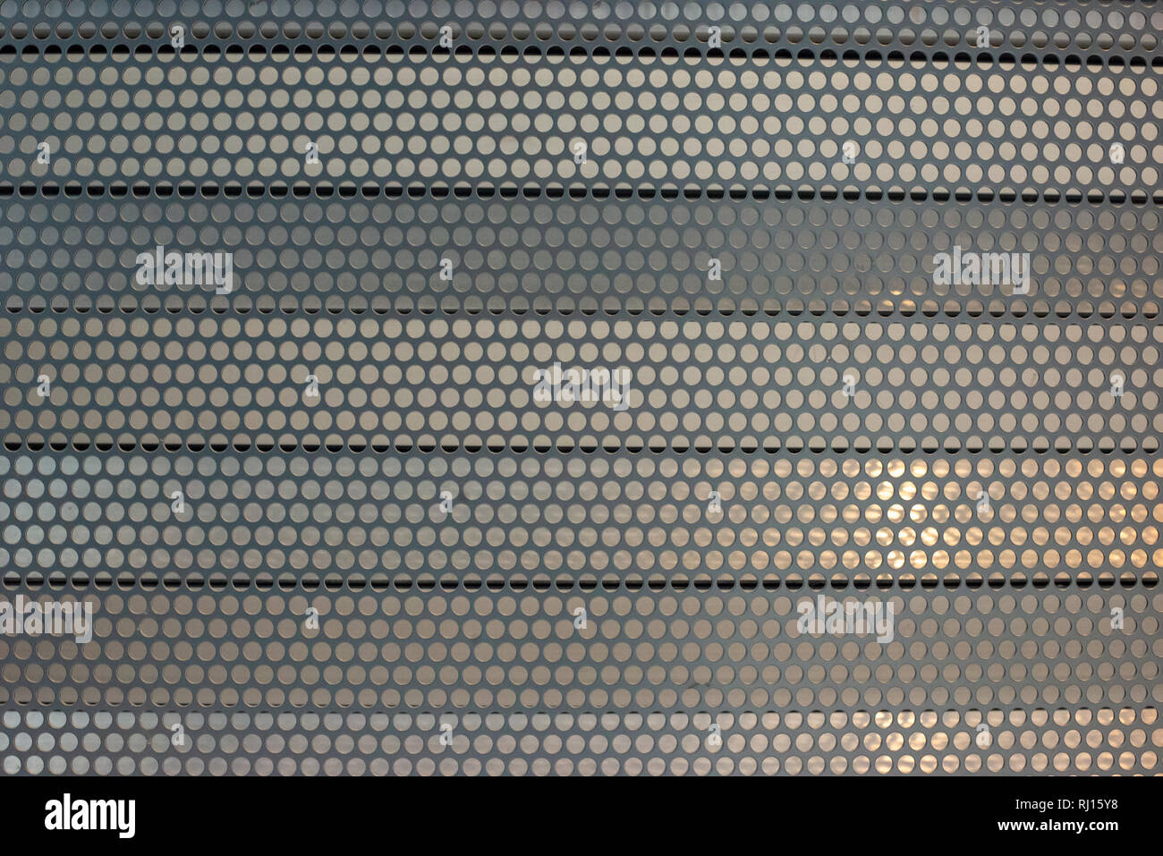 Metallplatte mit runden Löchern über parallele horizontale Jalousien aus Metall Hintergrund Textur. Stockfoto