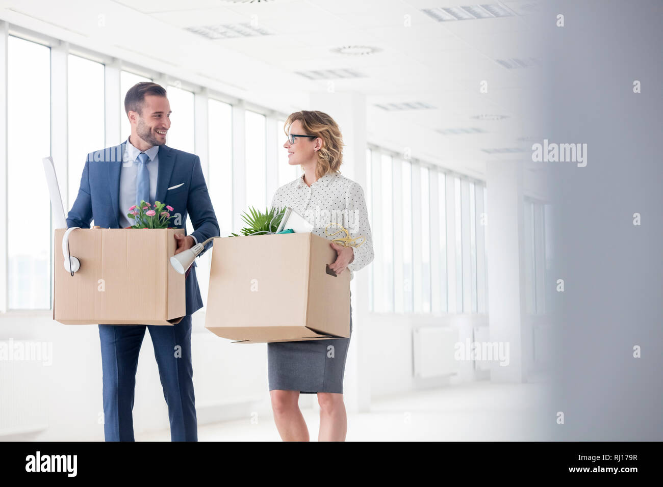 Lächelnd Kollegen die Kartons im neuen Büro Stockfoto