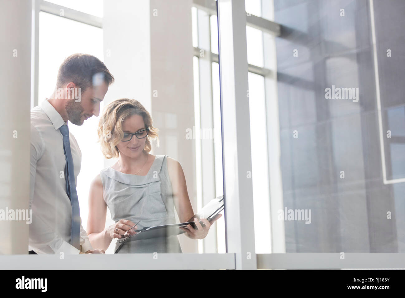 Geschäftsfrau diskutiert mit Geschäftsmann über Dokument im Büro Stockfoto