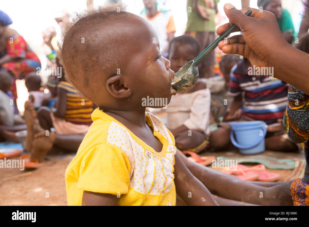 Samba Dorf, yako Provinz, Burkina Faso. Unterernährte Kinder essen nahrhaften Brei nach Gesundheit Arbeiter eine Demonstration der Methode. Stockfoto