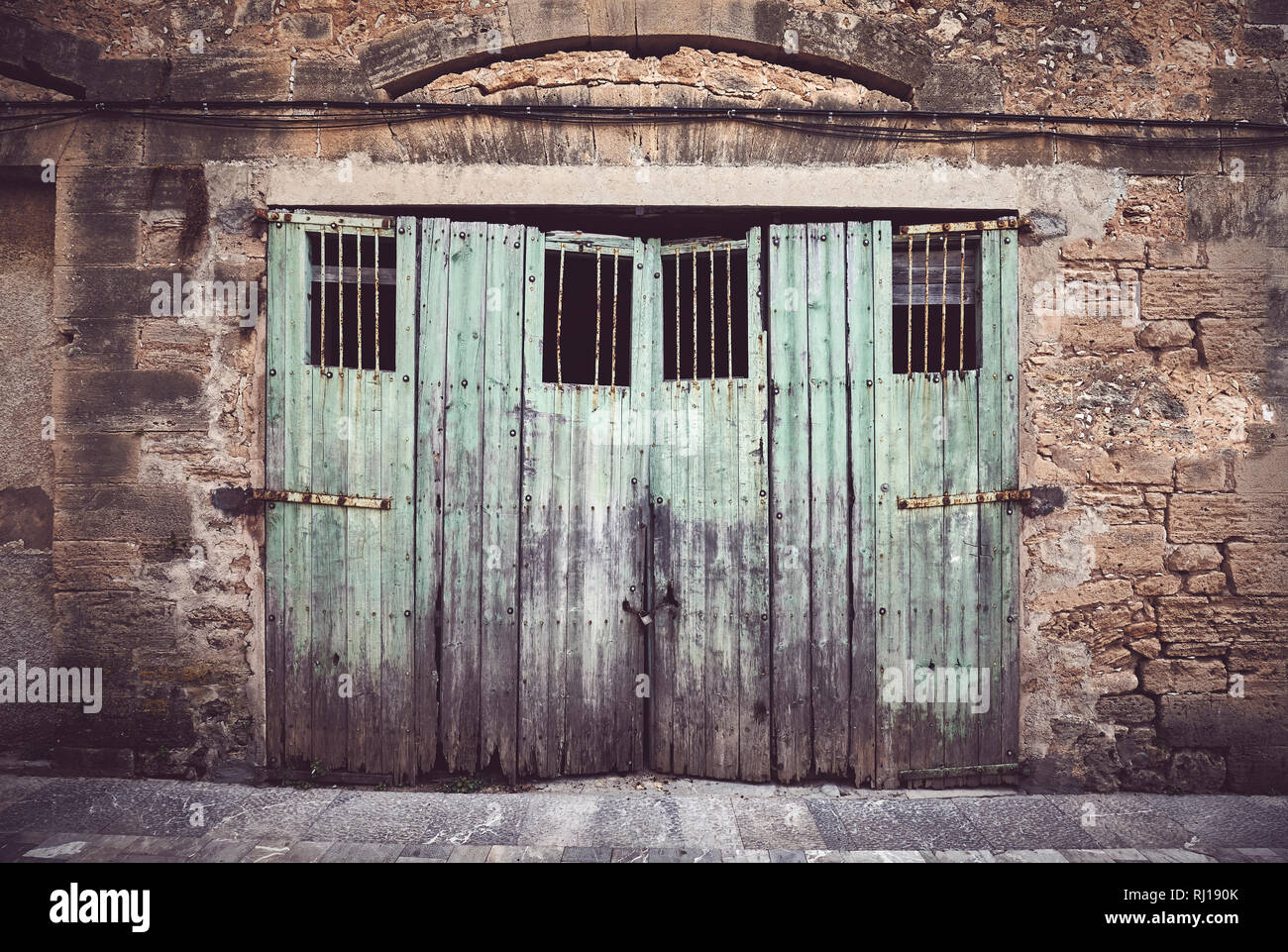 Alte Steinmauer mit Verwitterten hölzernen Tür, Farbe getonte Bild, Mallorca, Balearen, Spanien. Stockfoto