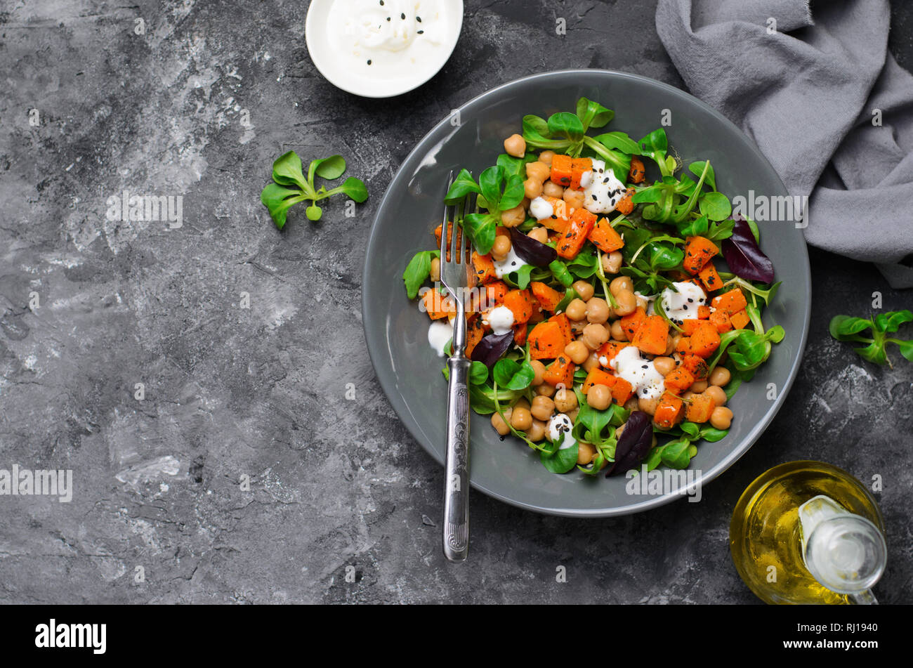 Gesunde vegetarische Salat, gerösteten Kürbis und Kichererbsen Salat in eine Schüssel auf grauem Hintergrund Stockfoto