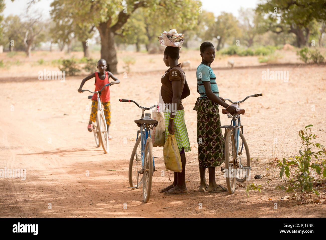 Samba Dorf, yako Provinz, Burkina Faso; Schülerinnen auf ihrem Weg von der Schule nach Hause warten im Schatten für einen Freund. Stockfoto