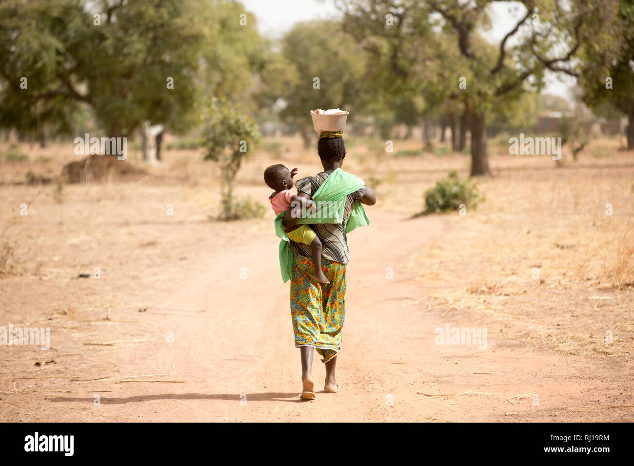 Samba Dorf, yako Provinz, Burkina Faso; Sally Zoundi, 35, mit ihrem Baby Salomon Zoundi, 15 Monate, auf ihre Weise auf der lokalen Goldmine zu arbeiten, um ihre Familie zu unterstützen. Stockfoto