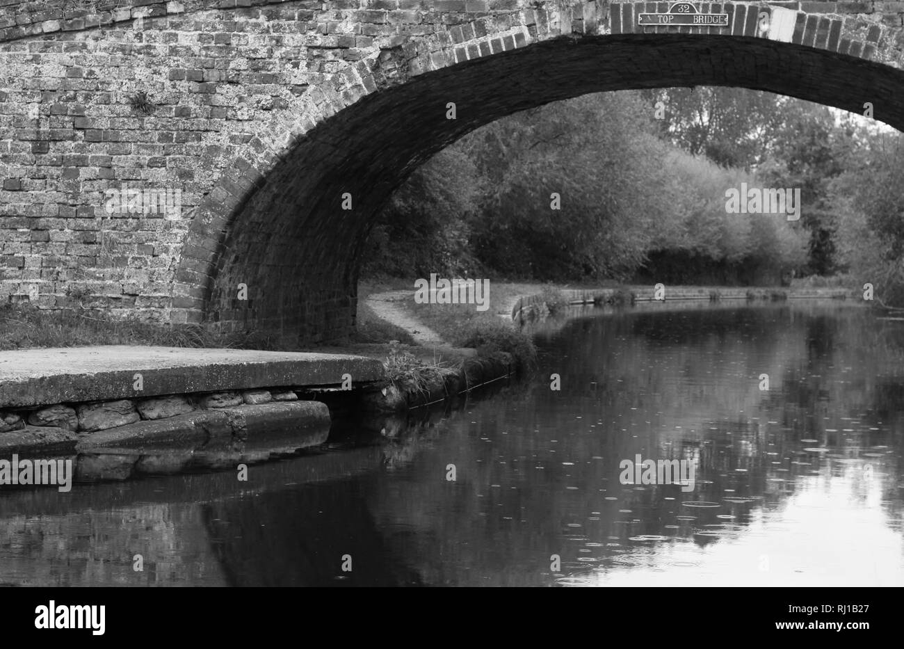 Bogenförmige Brücke über Wasser in Schwarz und Weiß Stockfoto