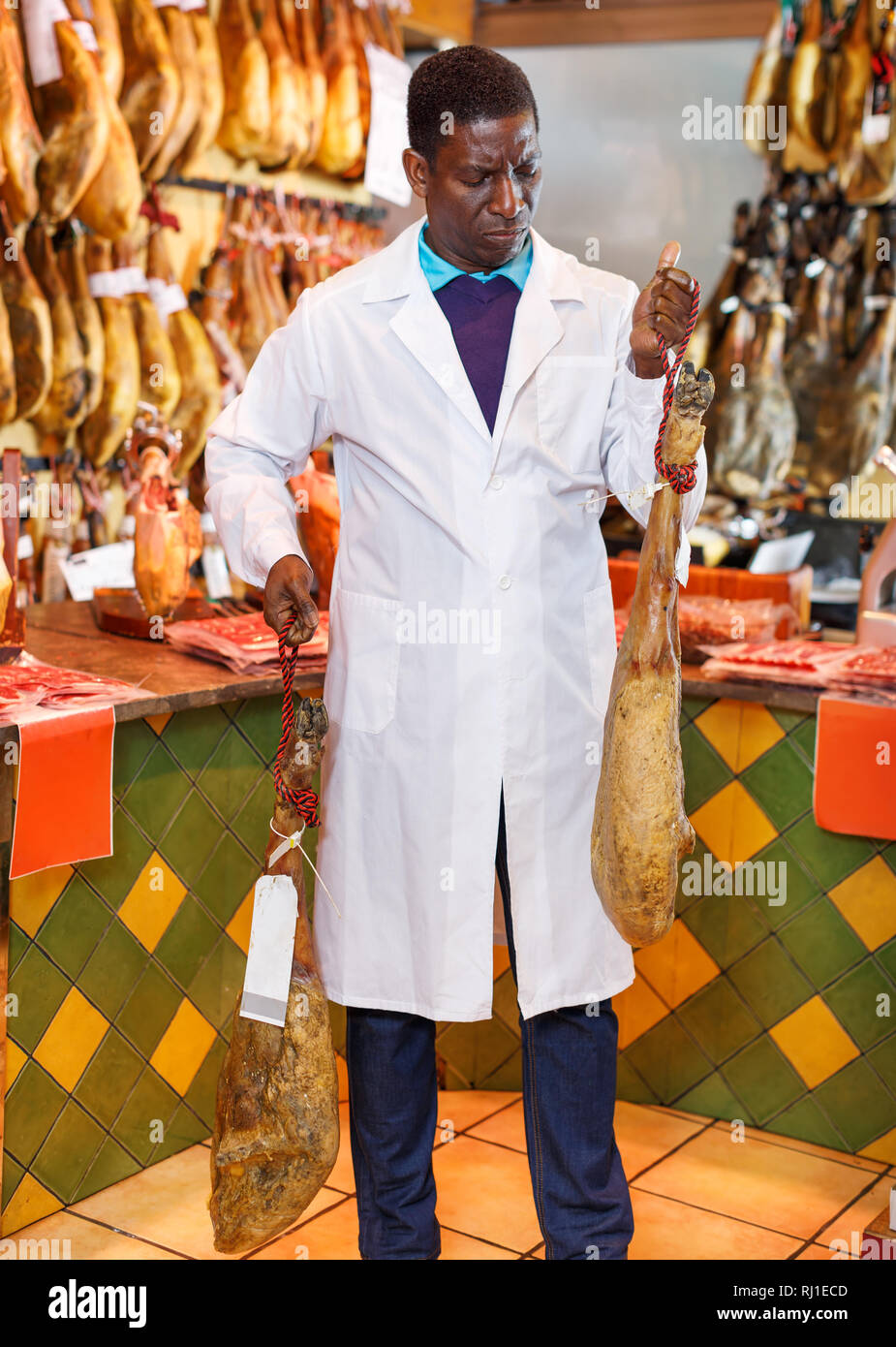 Zuversichtlich Afrikanische amerikanische Verkäufer Kontrolle der Qualität der Spanischen Schinken in Fleisch speichern Stockfoto