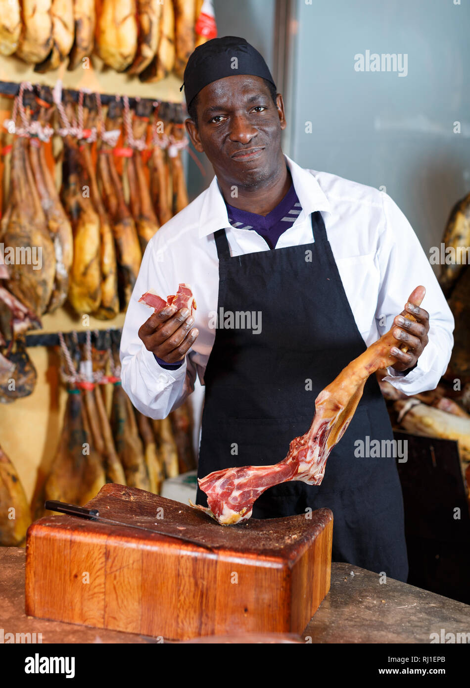 Happy African American Verkäufer in Fleisch shop arbeiten, empfehlen köstliche iberischen Schinken Stockfoto