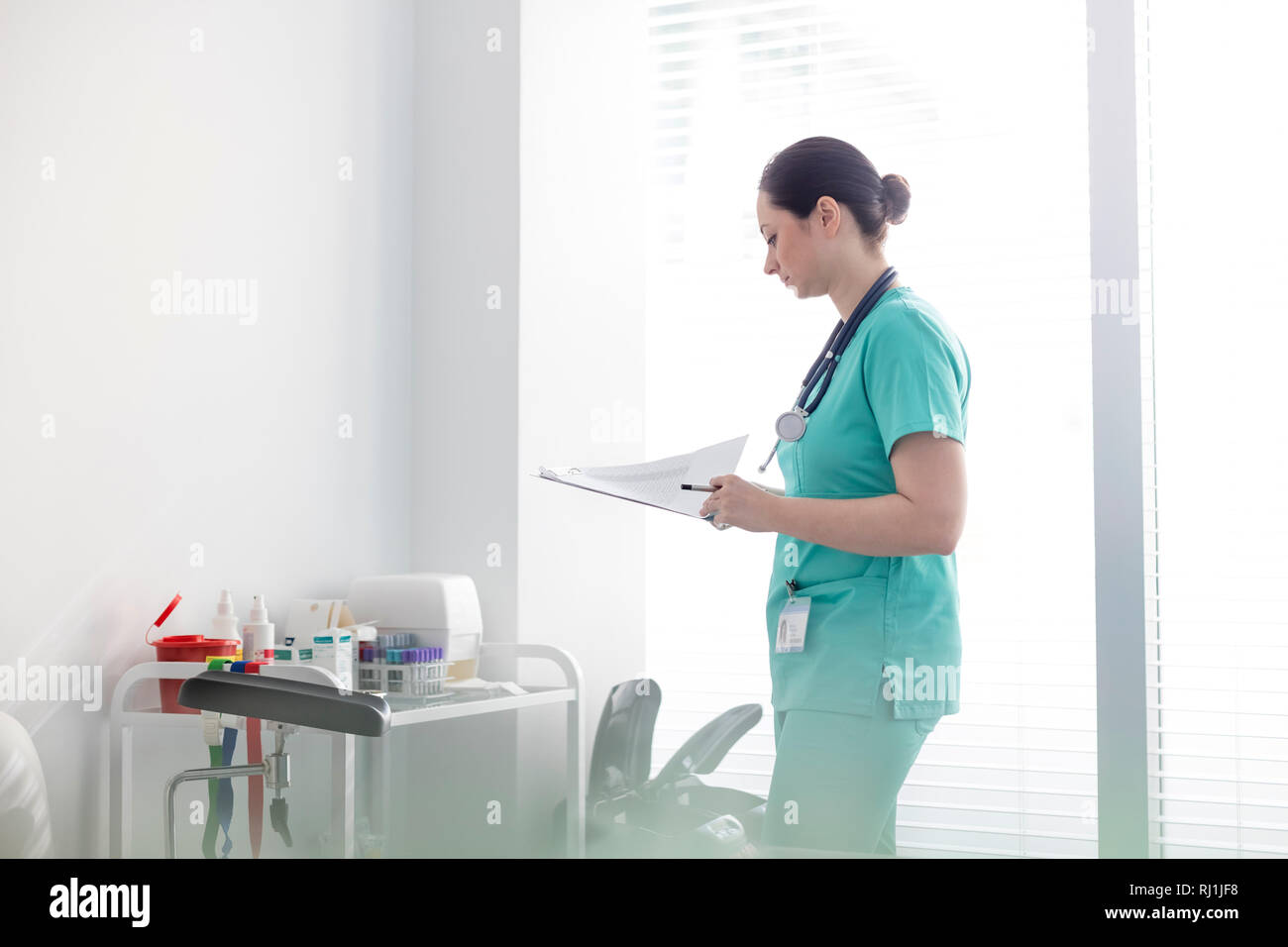 Mitte der erwachsenen Krankenschwester prüfen medizinische Berichte über die Zwischenablage an Krankenhaus Stockfoto