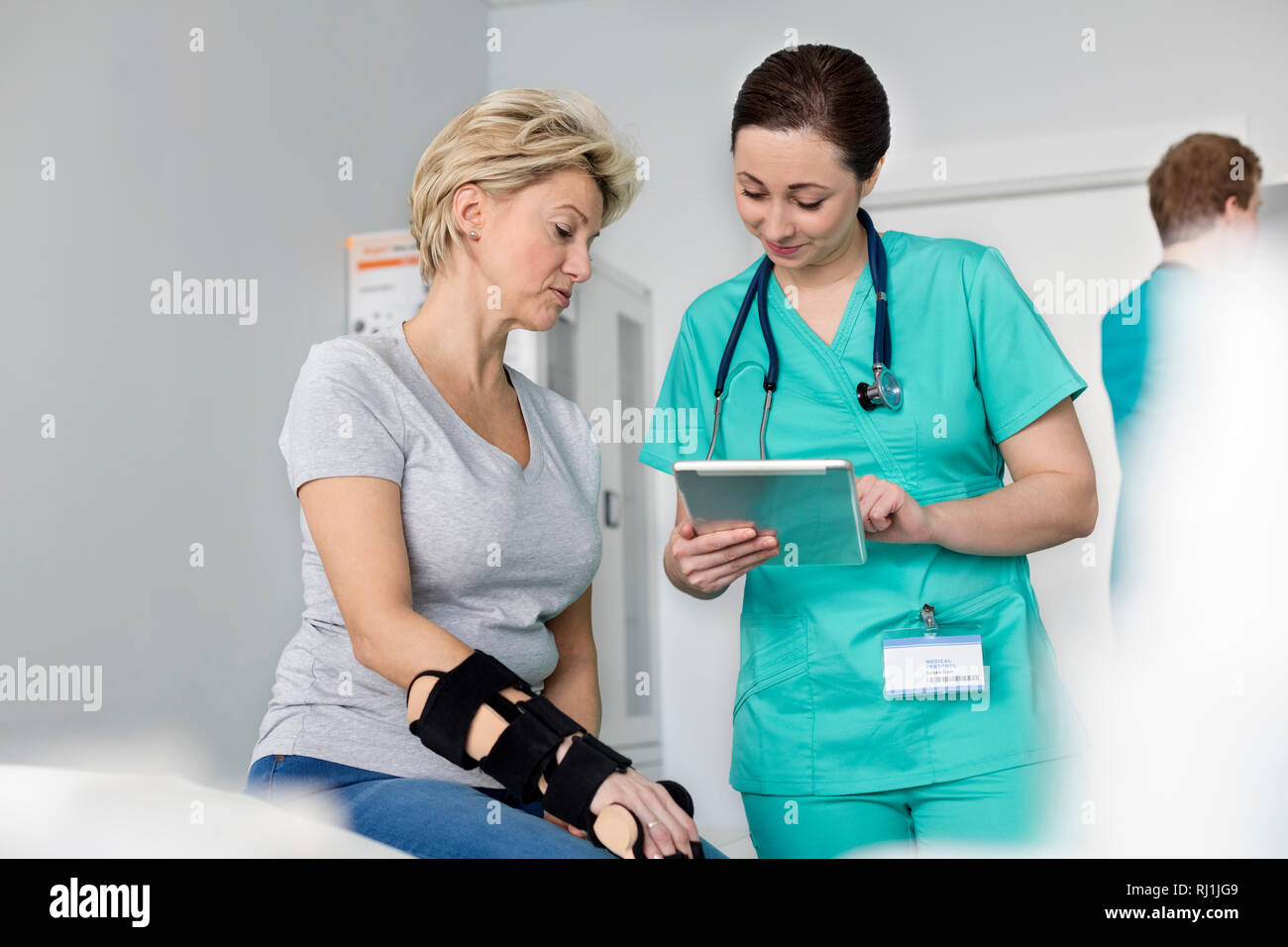 Krankenschwester mit medizinischen Bericht über digitale Tafel zu Frau mit Aussteifenden hand Stockfoto