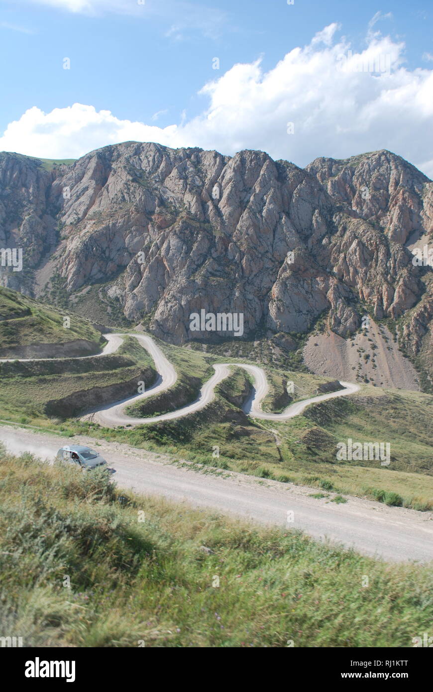 Ein Auto schlängelt sich über die serpentinen auf einem hohen Berg in Kirgisistan Stockfoto