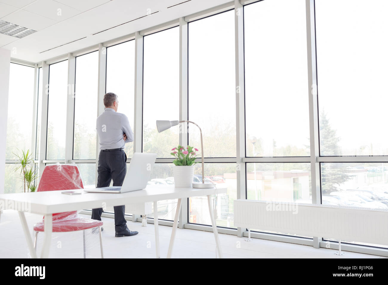 Volle Länge des nachdenklichen reife Geschäftsmann durch das Fenster im neuen Büro suchen Stockfoto