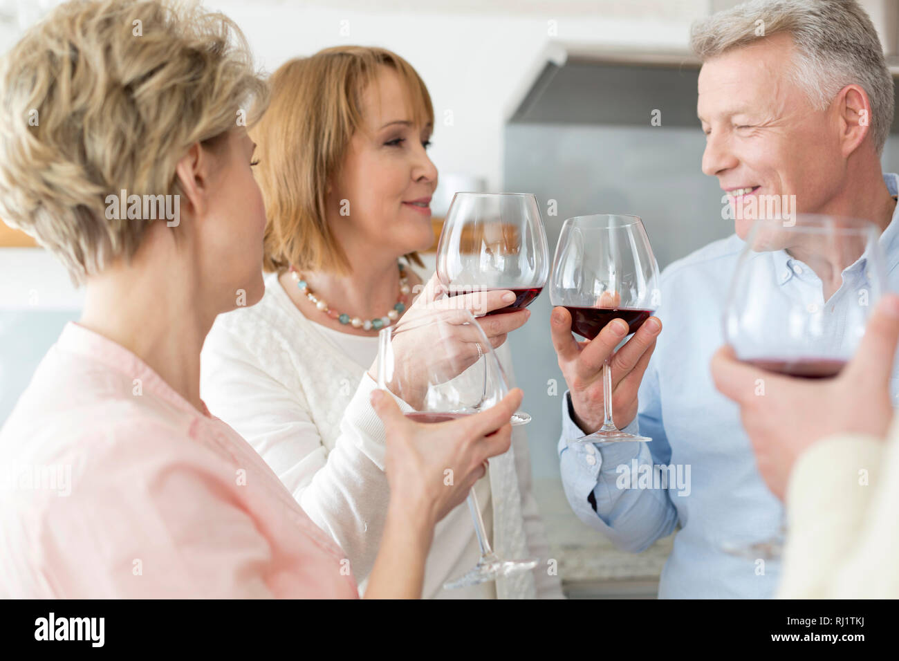 Gerne reifes Paar toasten Weingläser von Freunden zu Hause Stockfoto
