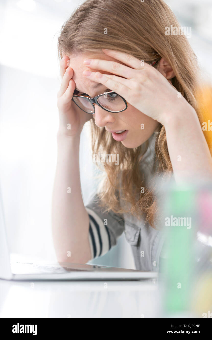 Überarbeitete Geschäftsfrau leiden unter Kopfschmerzen im Büro Stockfoto