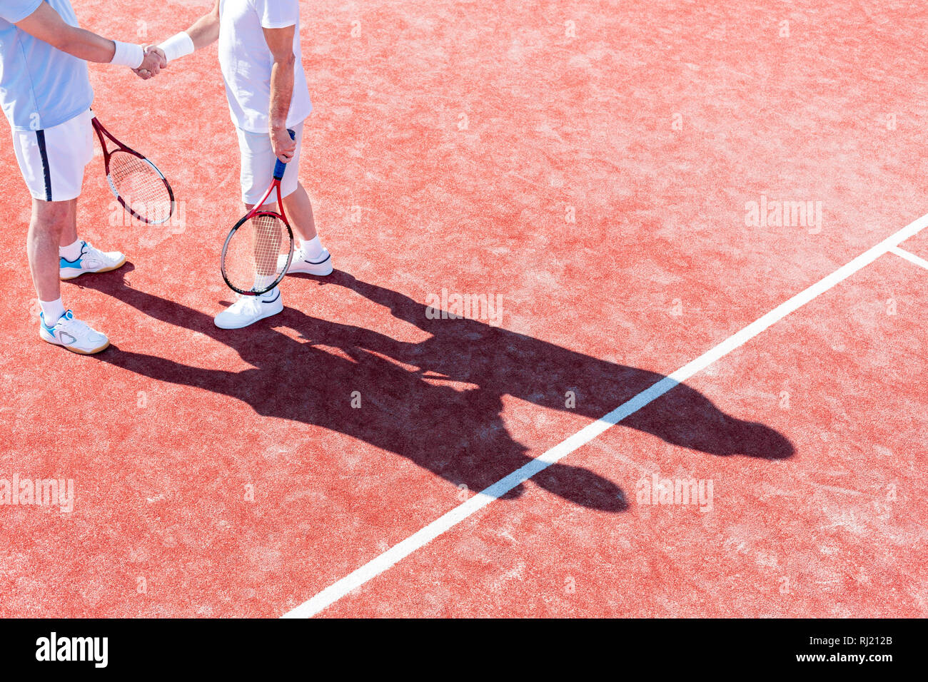 Untere Partie der Reife Männer die Hände schütteln beim Stehen auf Tennisplatz während des Spiels Stockfoto