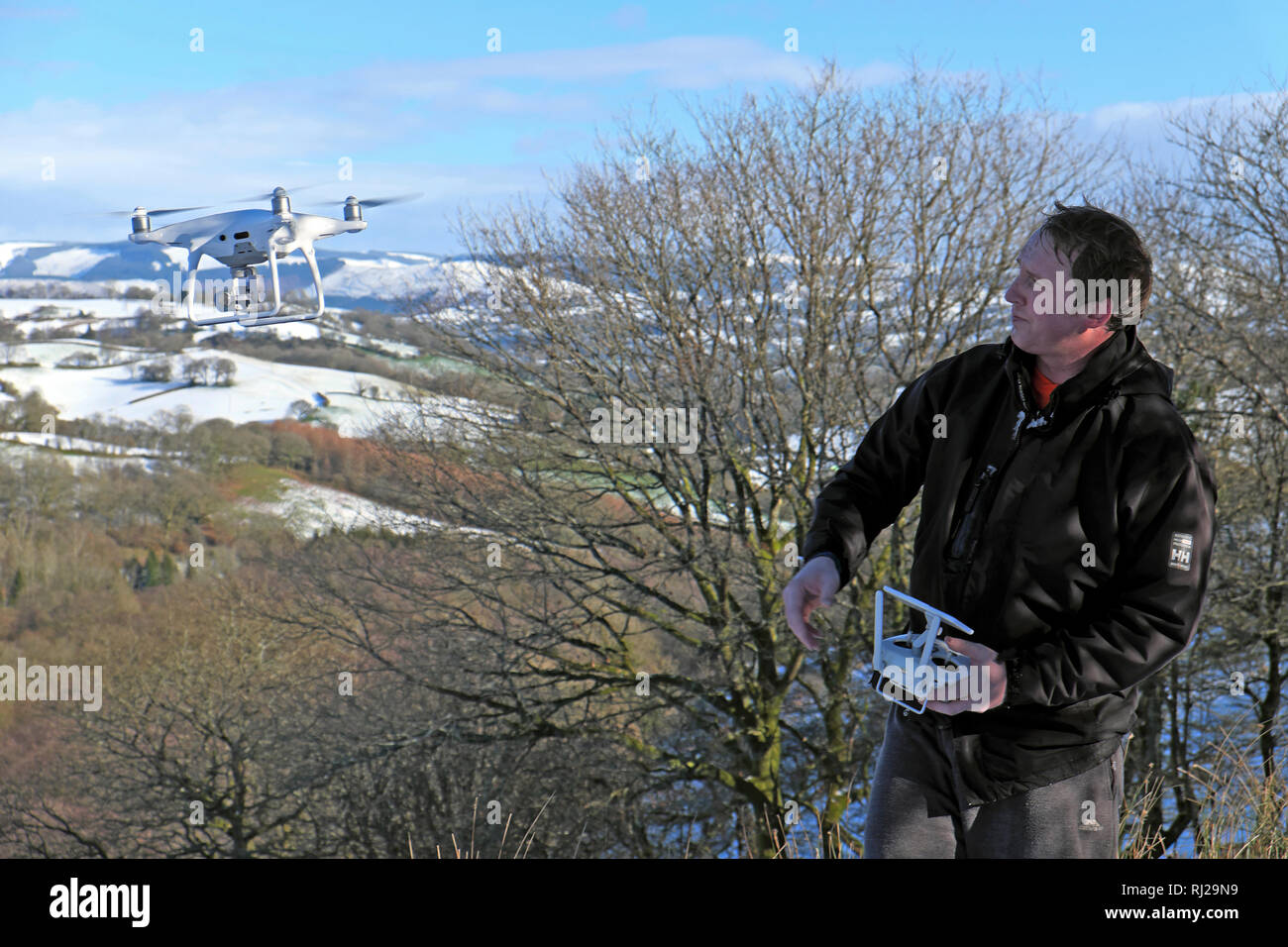 Ein Mann fliegen eine Drohne in ländlicher Winter verschneite Landschaft in der Landschaft von carmarthenshire Wales UK KATHY DEWITT Stockfoto