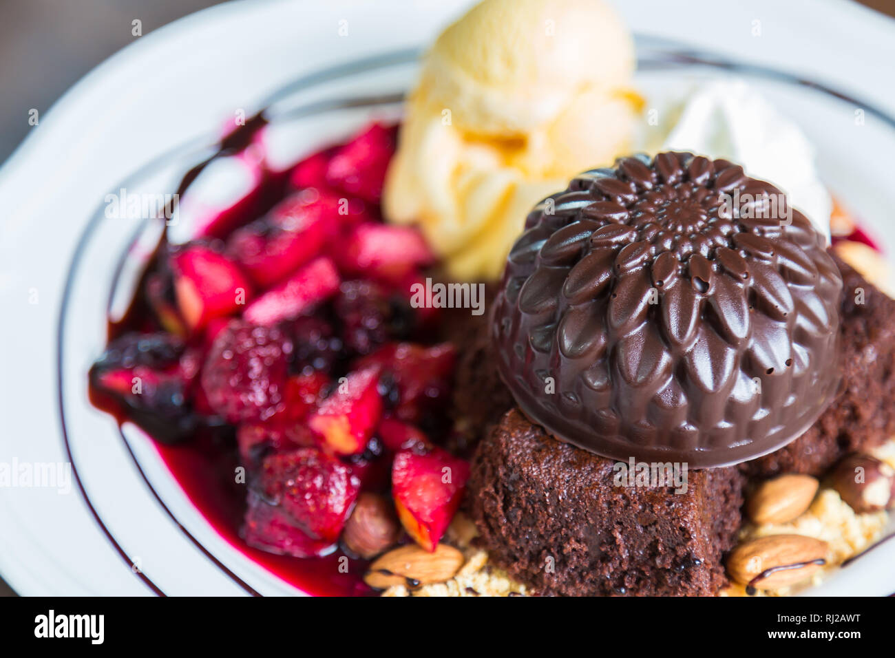 Schokoladenkuchen mit Früchten Pfirsich, schwarze Johannisbeere, Heidelbeere, Apfel, Eis Stockfoto