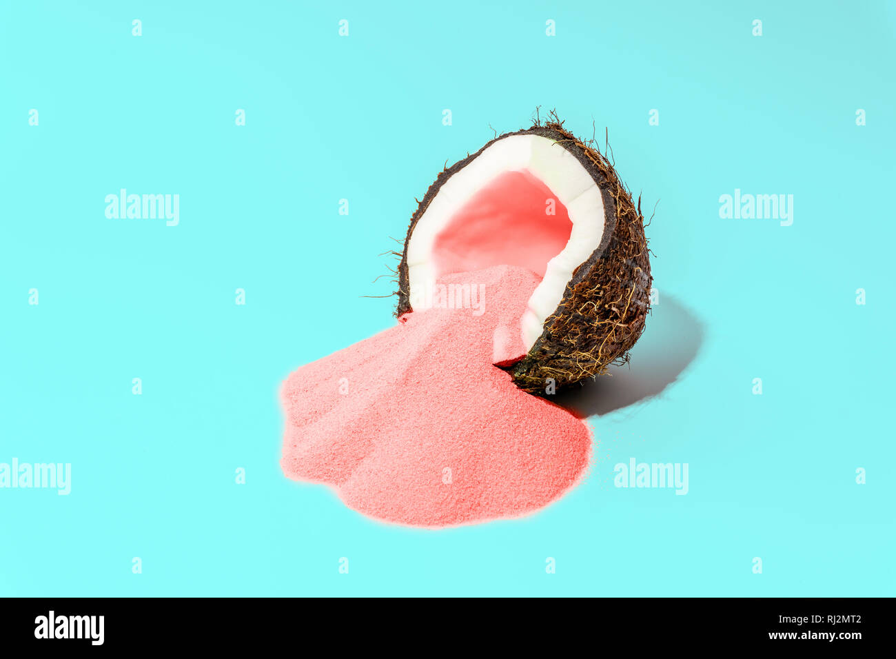 Sommer Konzept minimal. Hellen bunten Hintergrund mit Kokos und farbigen Sand in Pink und Türkis. Urlaub minimalen Begriff. Zeitgenössische ein Stockfoto