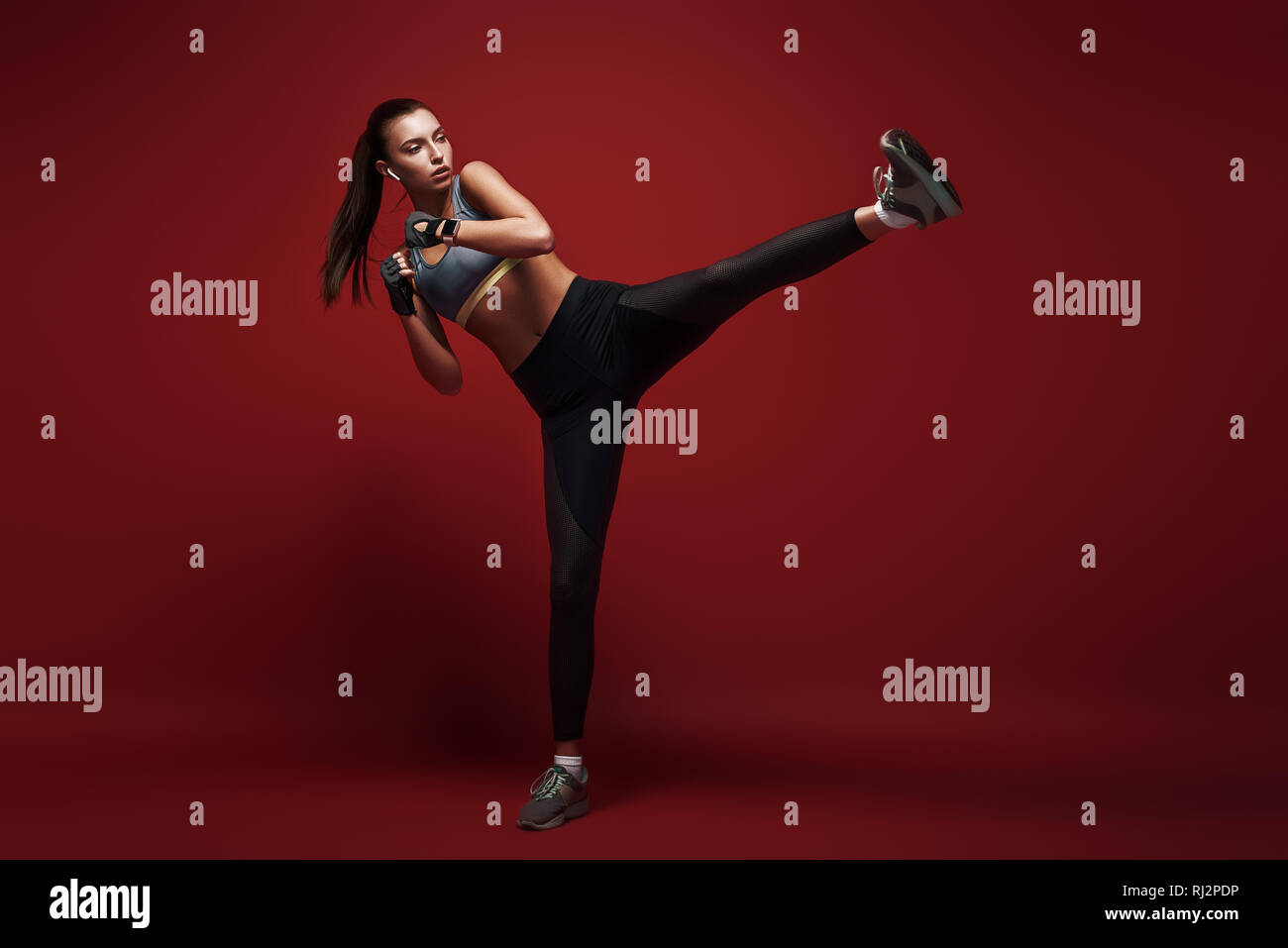 In voller Länge Porträt der jungen Sportlerin konzentriert tun Kickboxen Übungen über den roten Hintergrund isoliert Stockfoto