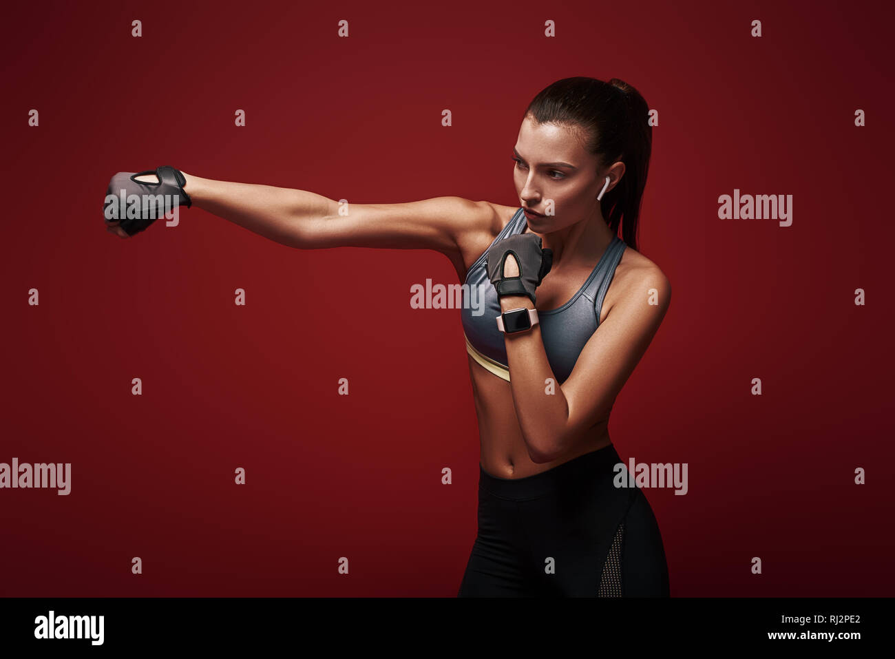 Porträt der jungen Sportlerin konzentriert tun Kickboxen Übungen über den roten Hintergrund isoliert Stockfoto