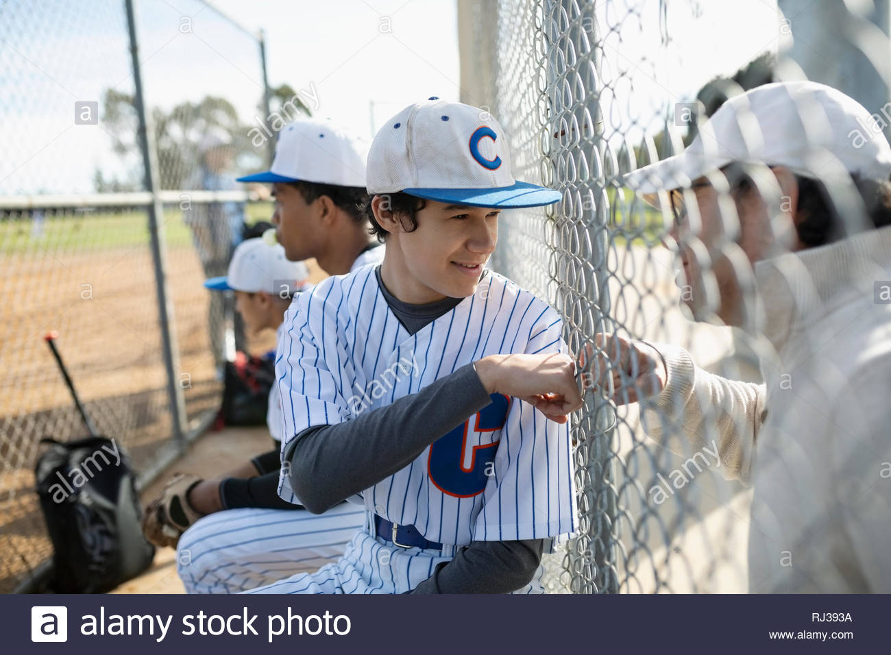Baseballspieler Faust stoßen Vati an Zaun Stockfoto