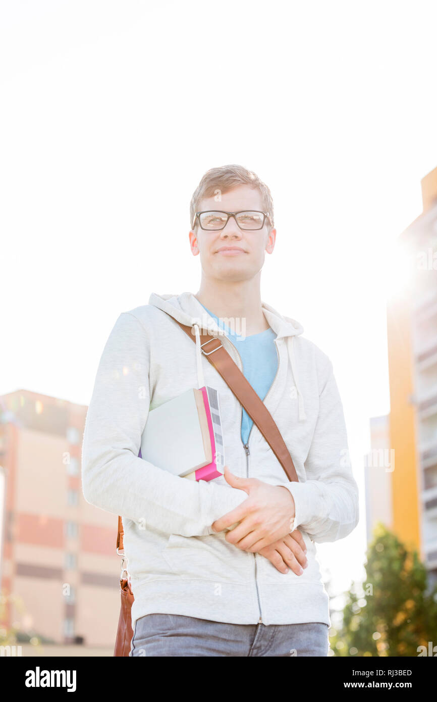 Portrait von Stattlichen student mit Büchern in Campus der Universität gegen Sky Stockfoto