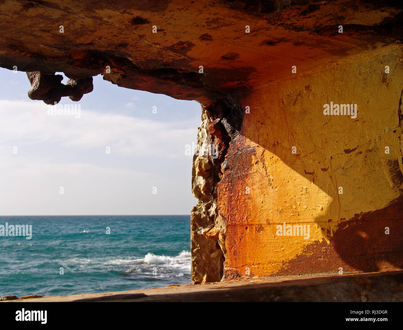 Ruhiger Blick auf Sommer Wellen des blauen Meer Wasser, durch erodierten Stein loch Bildung in Orange warme Farben Wand durch das Meer. Stockfoto