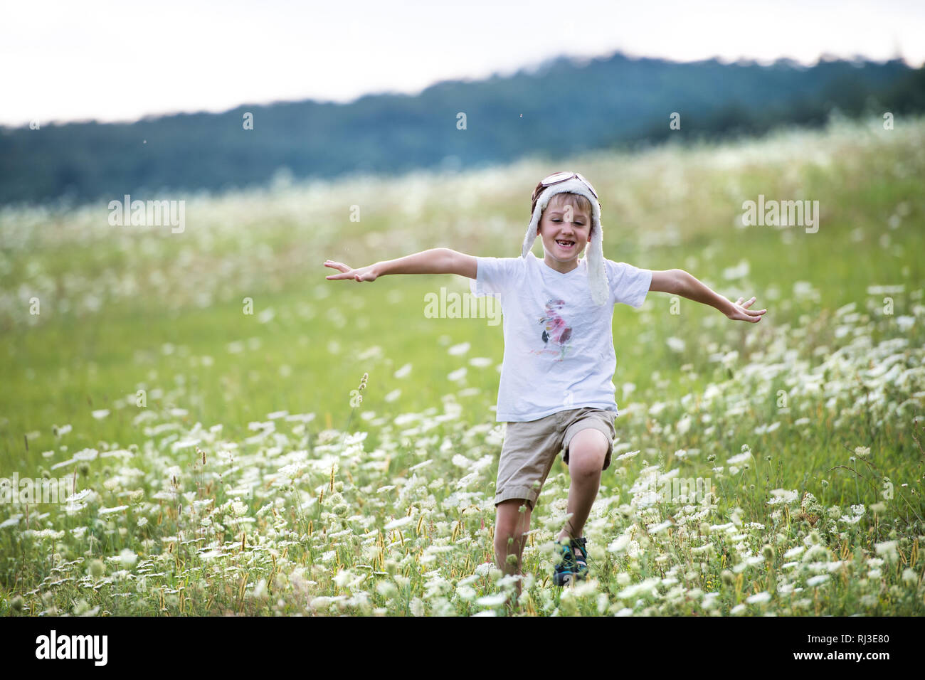 Ein kleiner Junge mit Pilot hat läuft in der Natur an einem Sommertag. Stockfoto