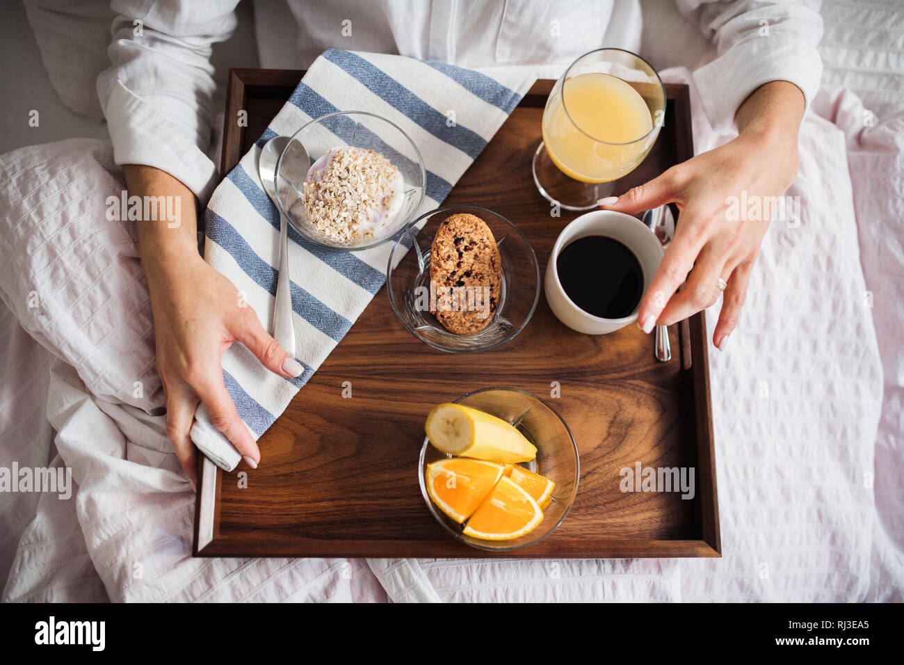 Ein Mittelteil der Frau mit Frühstück im Bett am Morgen. Eine Ansicht von oben. Stockfoto