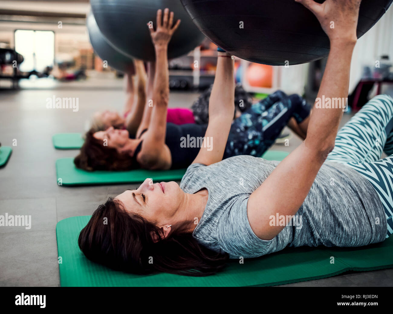 Eine Gruppe von fröhlichen Senioren in der Turnhalle tun Übung mit Sitz Bälle. Stockfoto