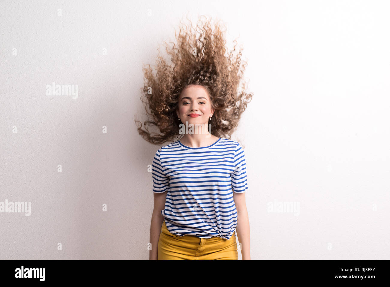 Junge schöne fröhliche Frau mit langen, lockigen Haar im Studio, springen. Stockfoto