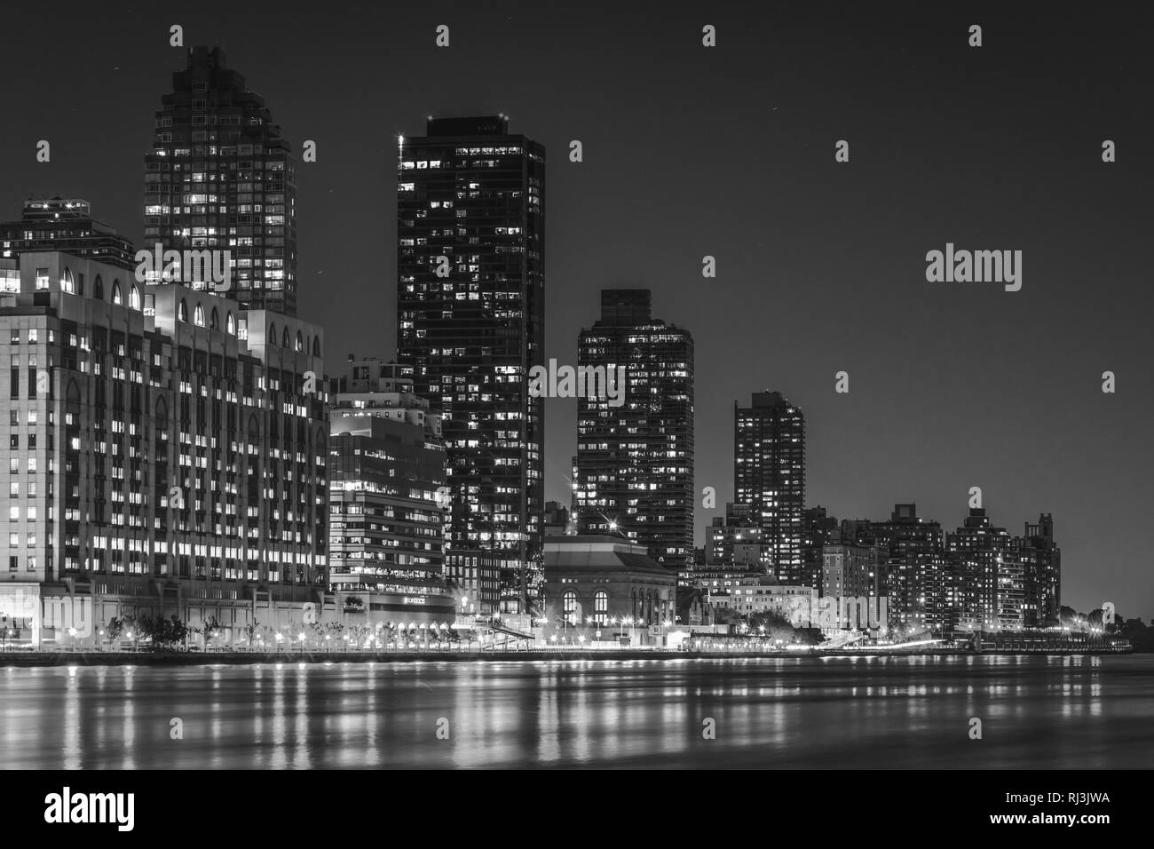 Die Skyline von Manhattan und dem East River in der Nacht, von Roosevelt Island, New York zu sehen. Stockfoto