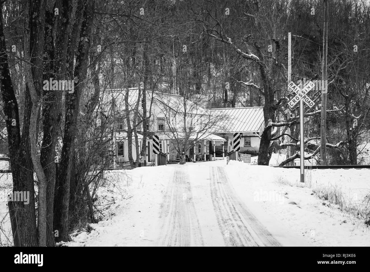 Brücke und Bahnübergang entlang einer Schnee bedeckten Landstraße, in einer ländlichen Gegend von Carroll County, Maryland. Stockfoto