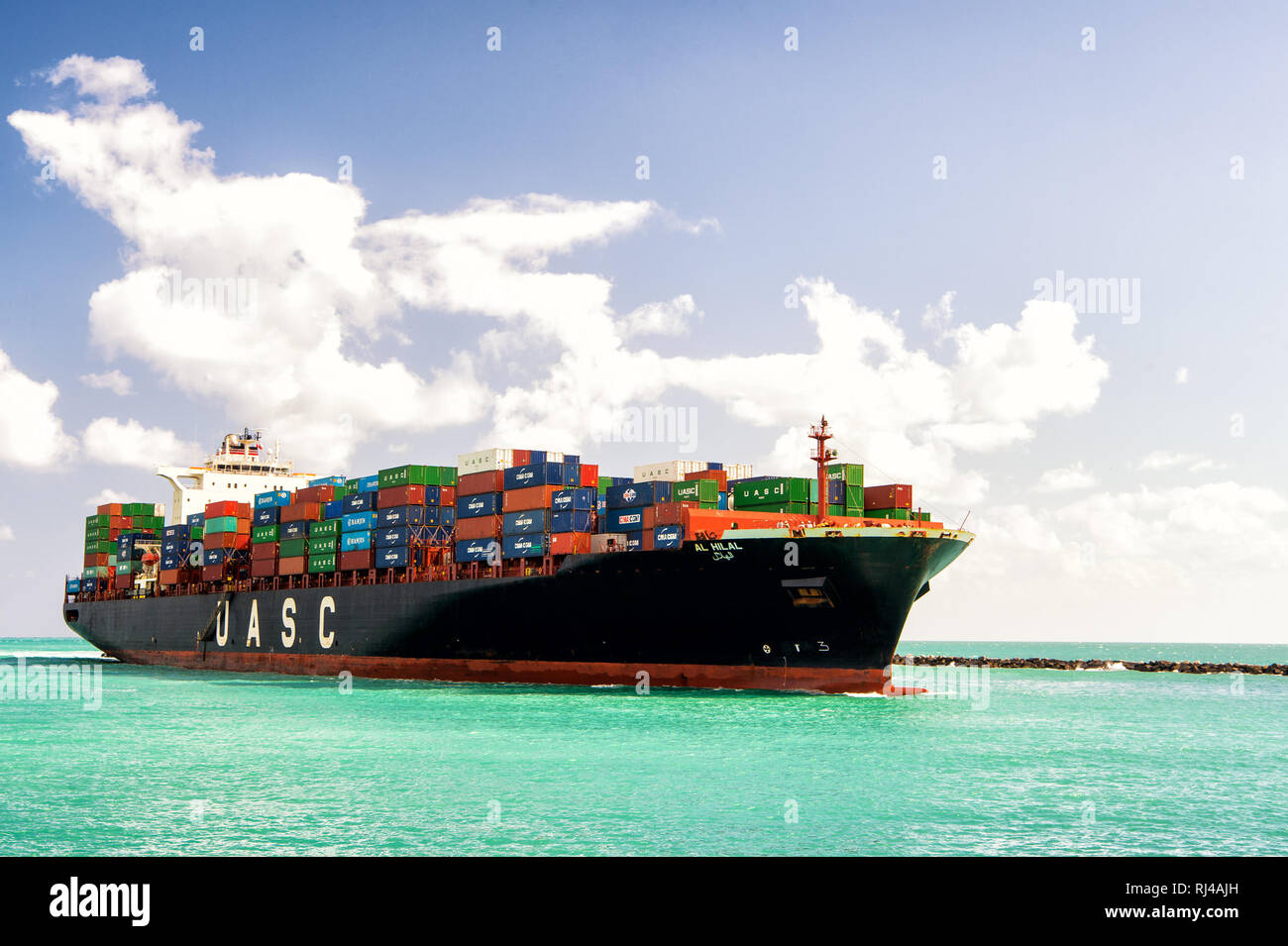 Miami, FL, USA - 19. Februar 2016: Große schwarze Frachtschiff UASC mit vielen Shipping Container am Meer Wasser und bewölkter Himmel segeln weiter nach Miami Beach zu soth Stockfoto