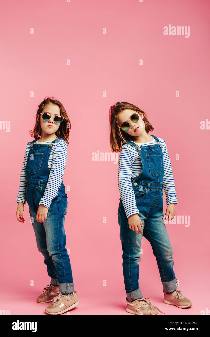 Stilvolle nette Mädchen Kleidung tragen. Mädchen posieren in Jeans Latzhose  auf rosa Hintergrund Stockfotografie - Alamy