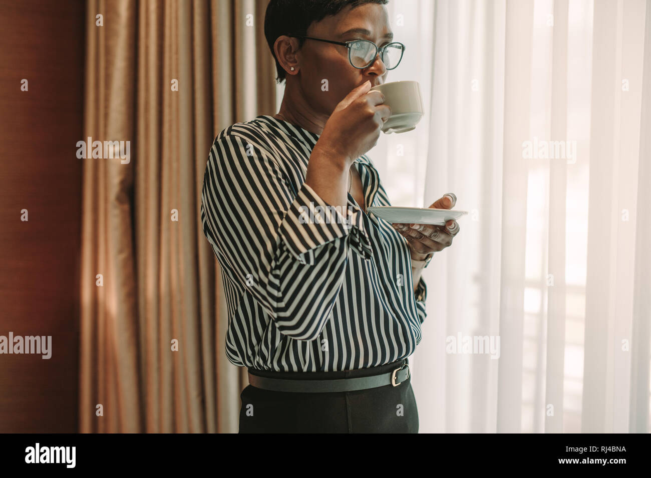 Reife Frauen in formelle Kleidung in Kaffee im Zimmer. Geschäftsfrau auf Geschäftsreise trinken Kaffee im Hotel Zimmer. Stockfoto