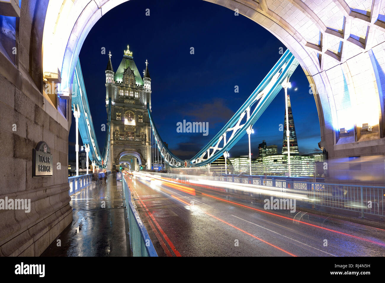 Hell erleuchtete die Tower Bridge in London bei Nacht, Leuchtspuren fahrender Autos Stockfoto