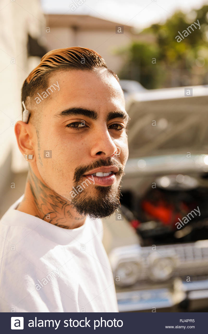 Portrait zuversichtlich, coole Latinx junger Mann mit Tattoos und Marihuana gemeinsame hinter dem Ohr Stockfoto