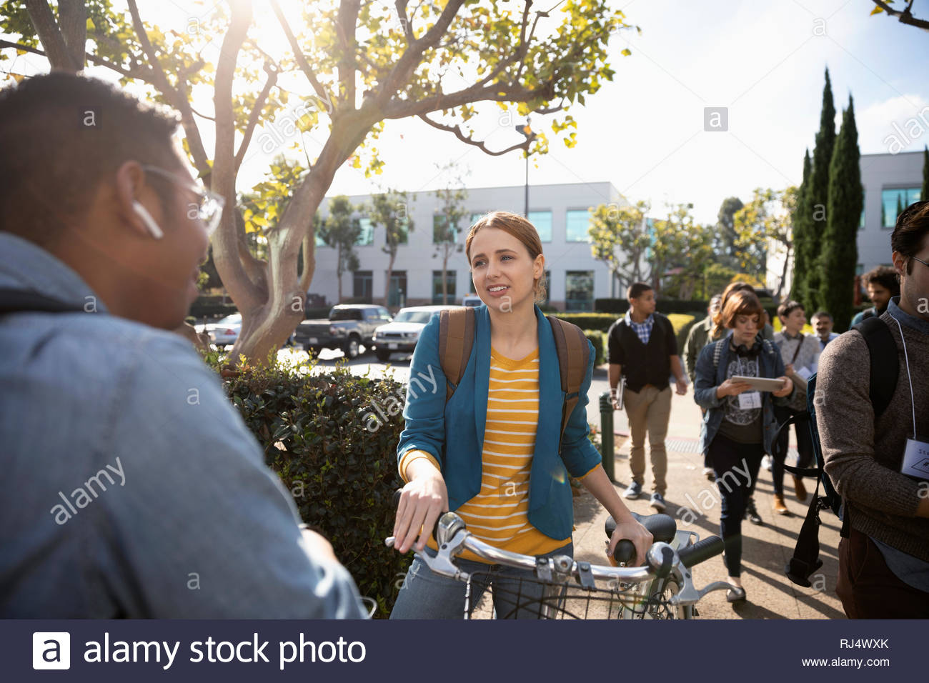 Geschäftsfrau mit Fahrrad im Gespräch mit Kollegen auf dem Parkplatz Stockfoto