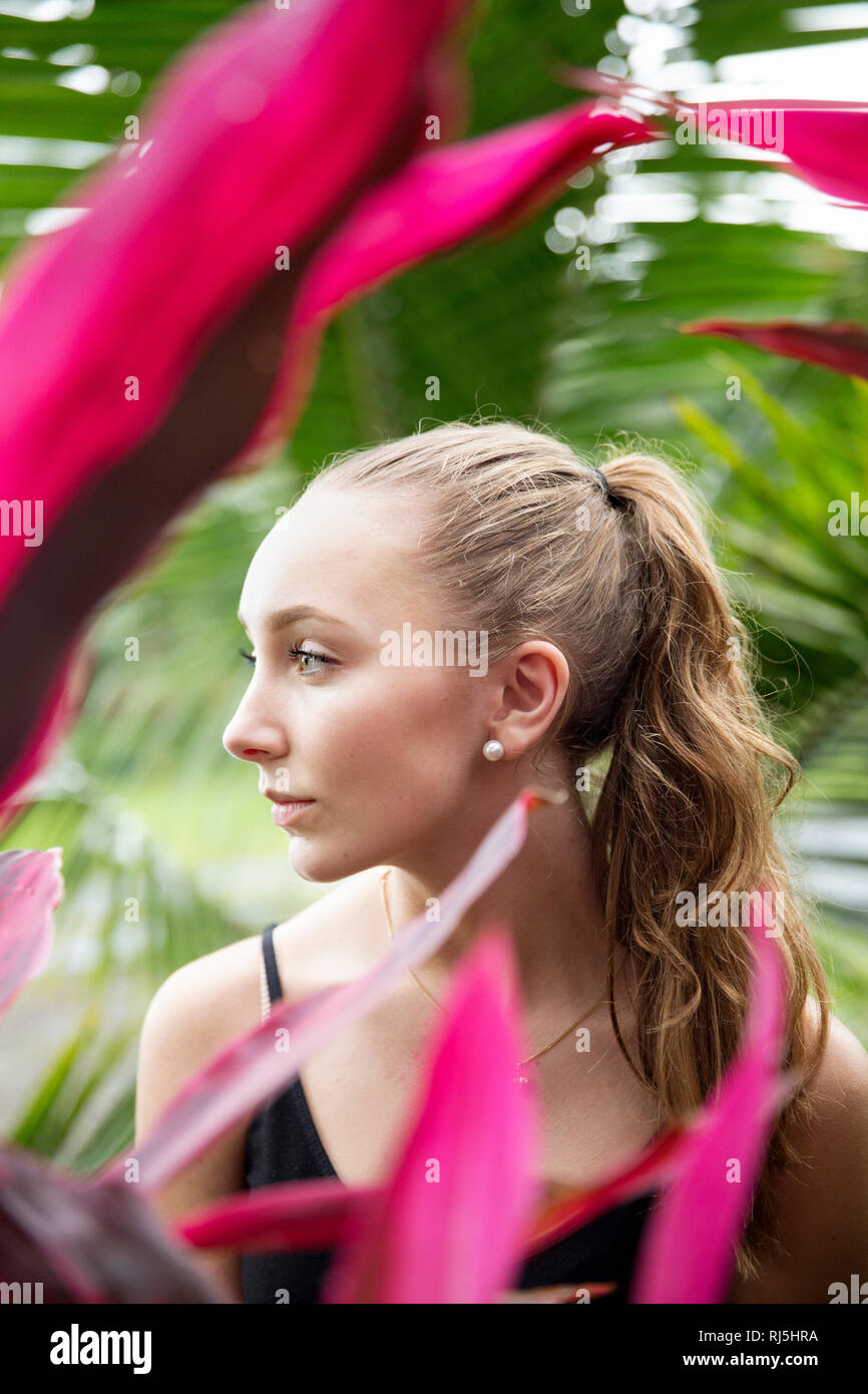 Porträt der jungen Frau mit rosa Anlage im Vordergrund. Stockfoto