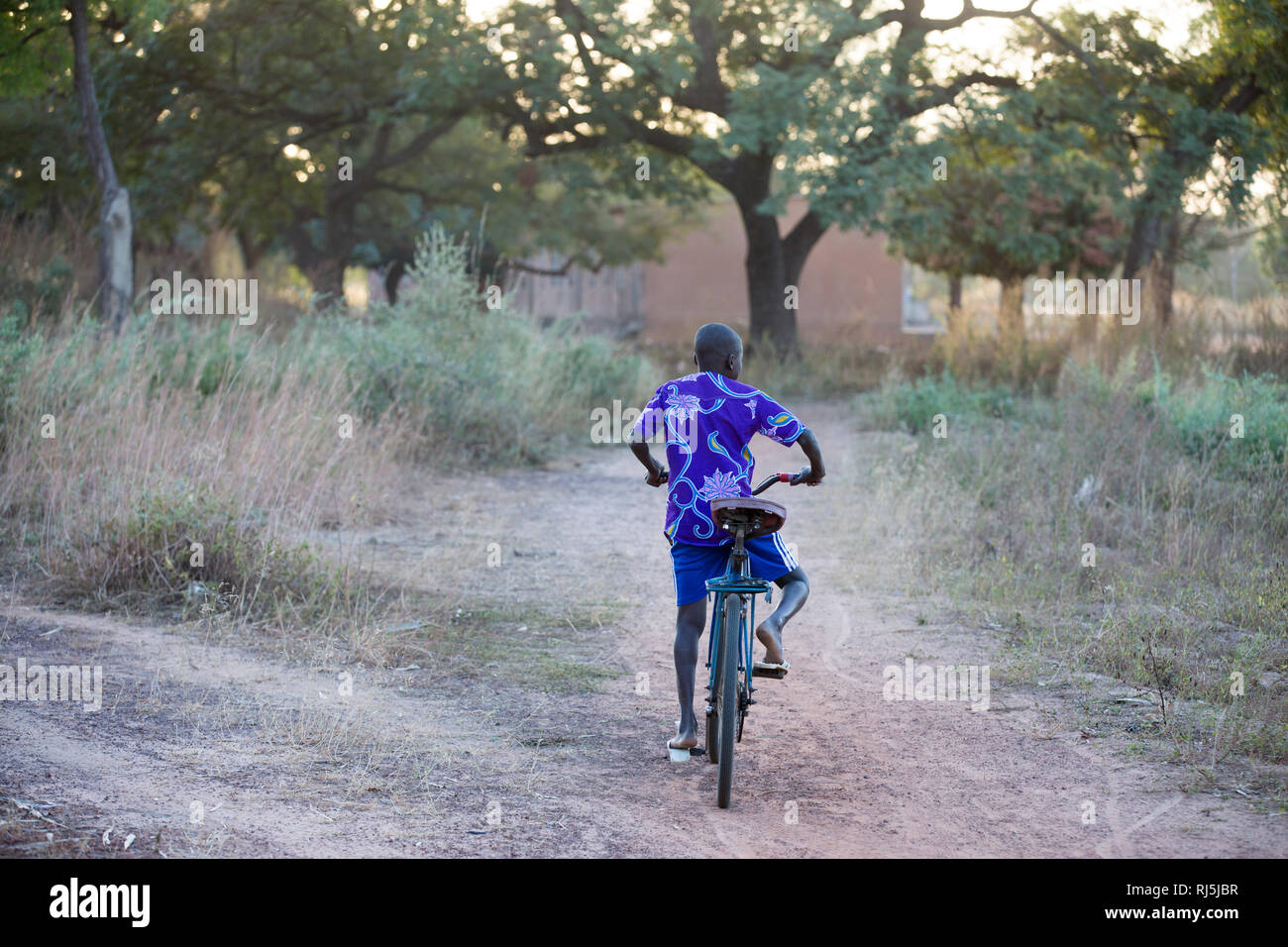 Bodadiougou Dorf, Banfora, Cascades Region, Burkina Faso, 4. Dezember 2016; EIN Junge auf seinem Fahrrad durch den Ort. Stockfoto