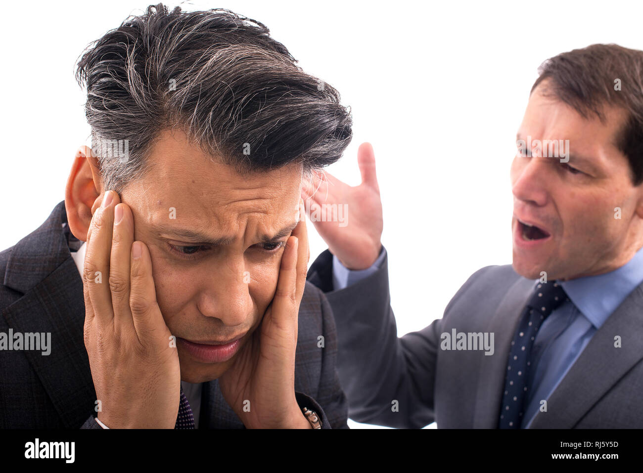 Zwei Geschäftsleute haben ein Argument vor einem ganz weißen Hintergrund: Ein Mann hat seinen Kopf in den Händen, der andere schreit ihn an. Stockfoto