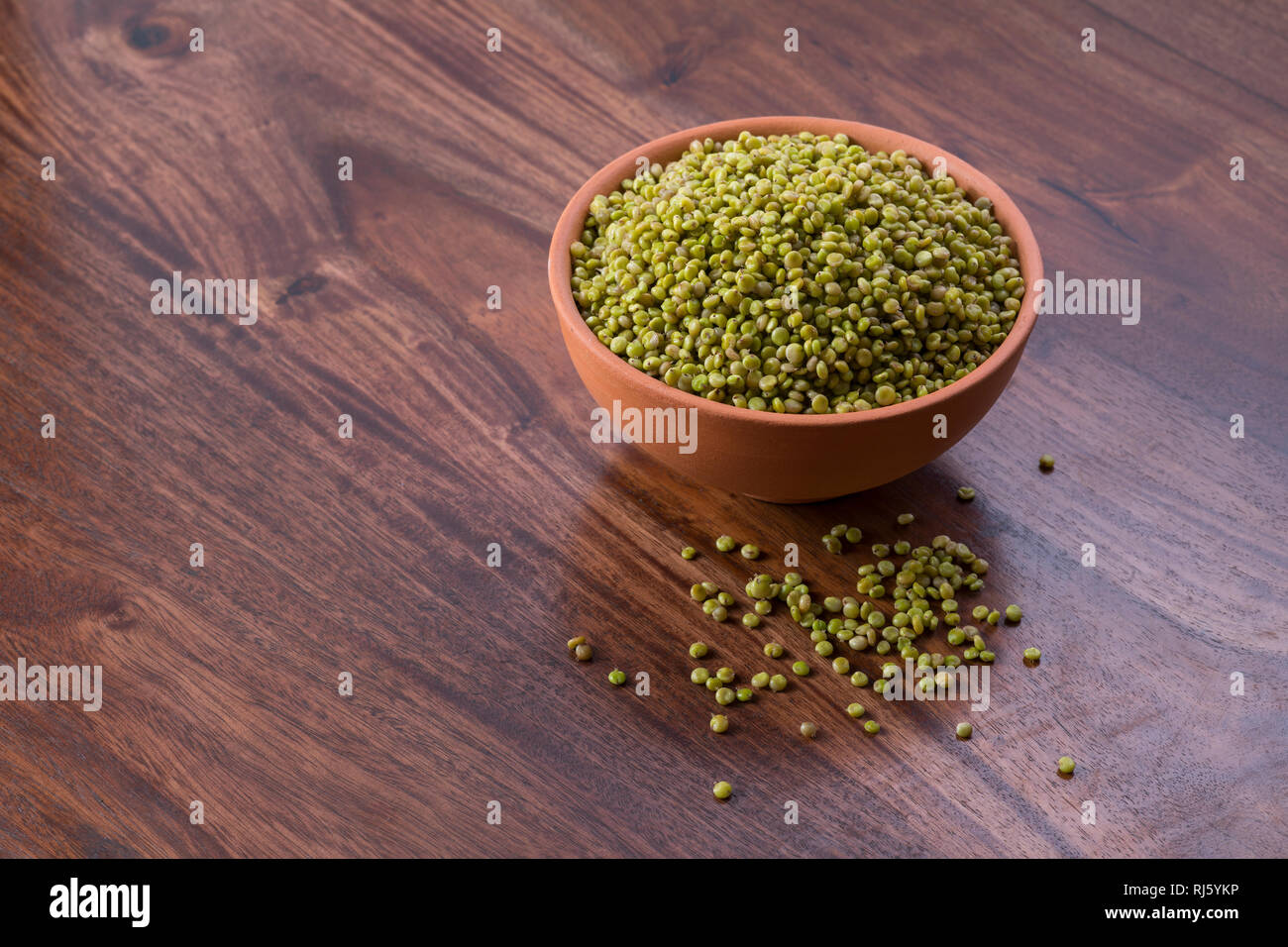 Frisches Grün Ausschreibung Sorghum in einem irdenen Schüssel auf Holz- Hintergrund Stockfoto